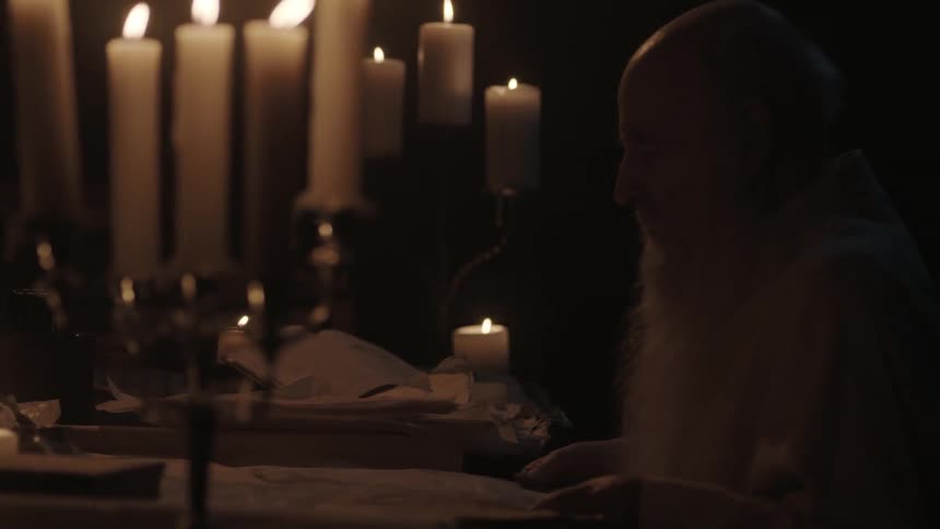 A man is looking through papers by candle light