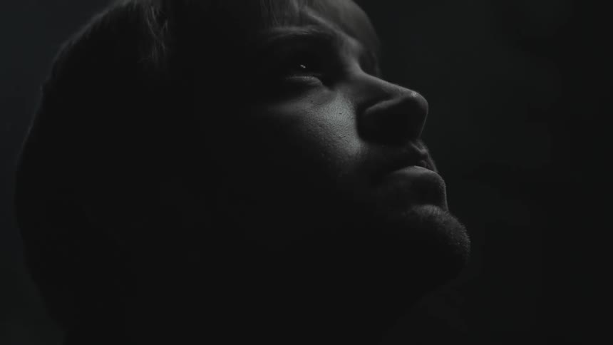 A man looks up in a dark area