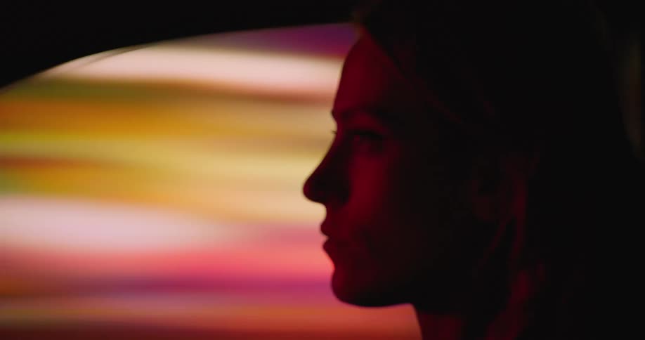 Side profile of woman driving car in illuminated city streets at night