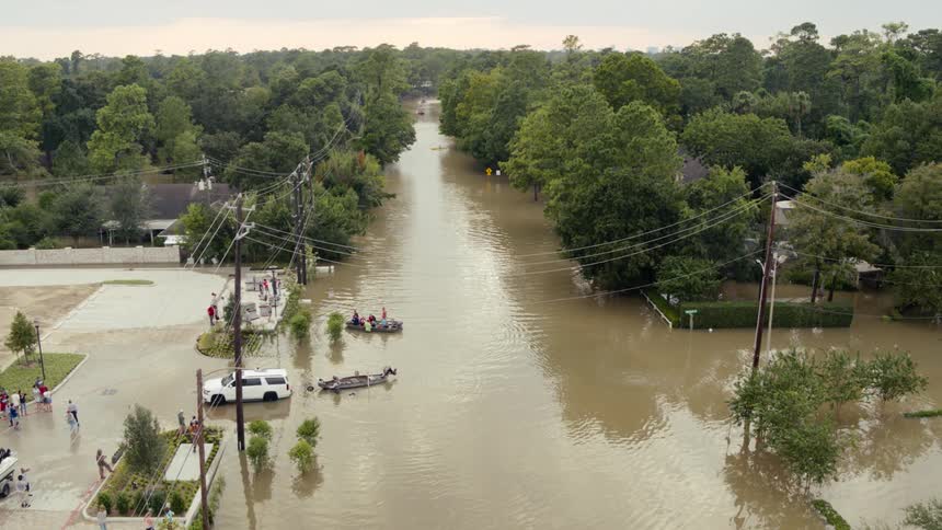 Boat moves along flooded street in flooded neighborhood helping people