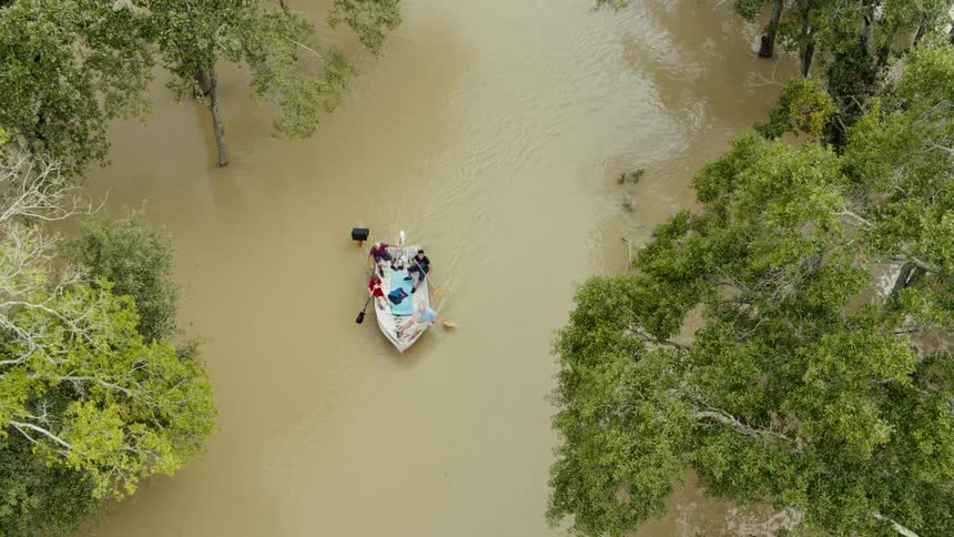 Aerial view of 4 people paddling in a boat down a river