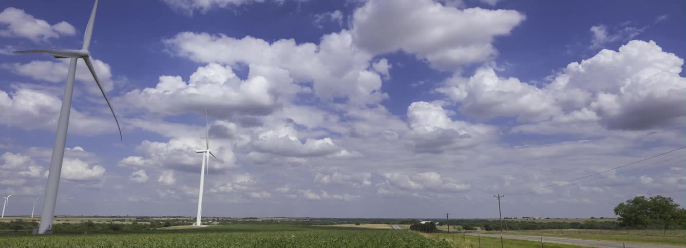 Wind turbines operate in the green field near the road in the countryside
