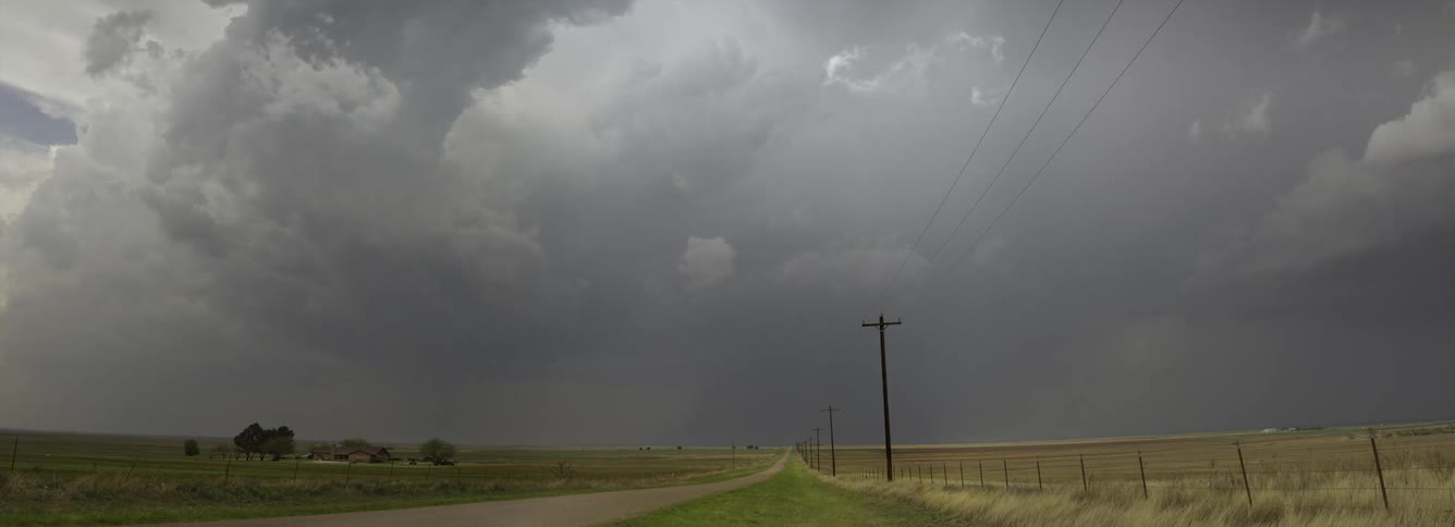 Storm clouds move over a rural area and a road lined with utility poles
