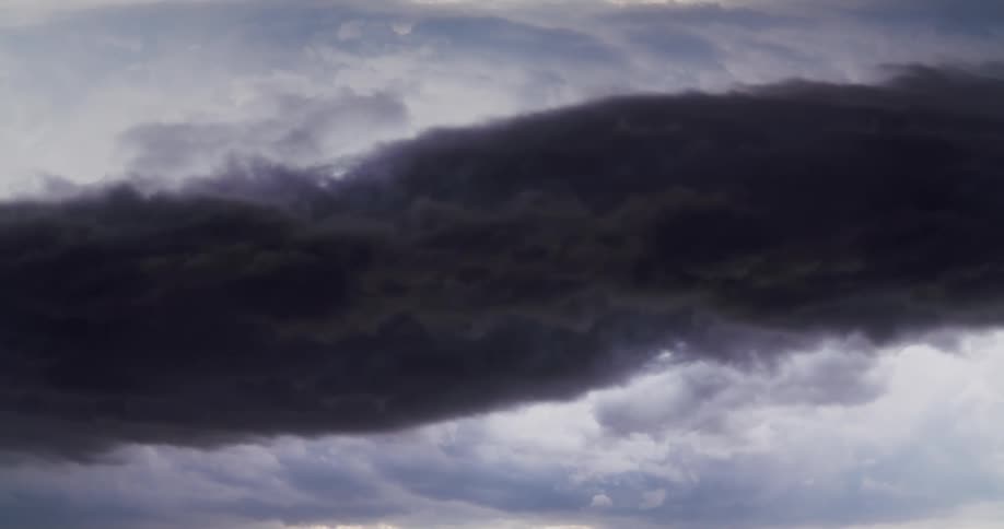 A dark line of clouds surrounded by lighter clouds in the distance