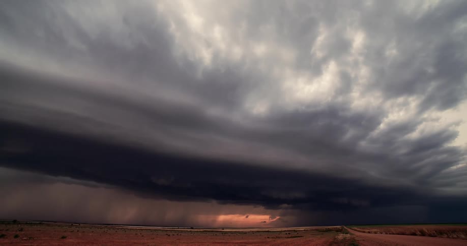 Dark storm clouds move across the sky pouring rain on a rural area