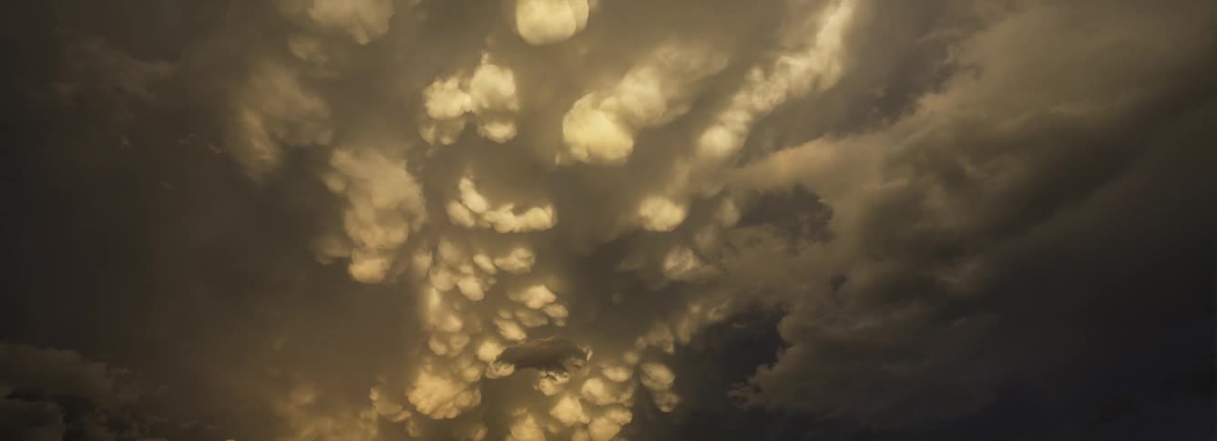 White clouds move across the sky as darker clouds move in and lightning flashes