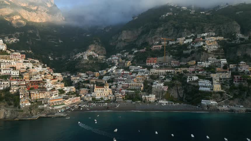 Buildings scattered across the landscape at the foot of mountains and the edge of the water