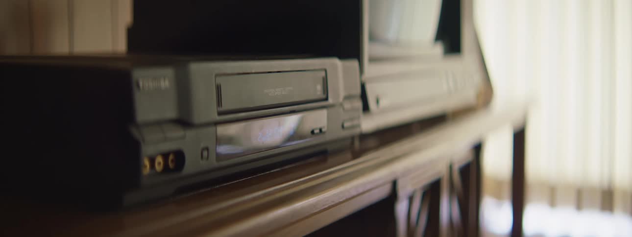 Someone pushes a button on a vcr and a tape pops out and they take it