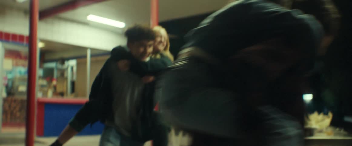 Teenagers run around and eat food by the restaurant
