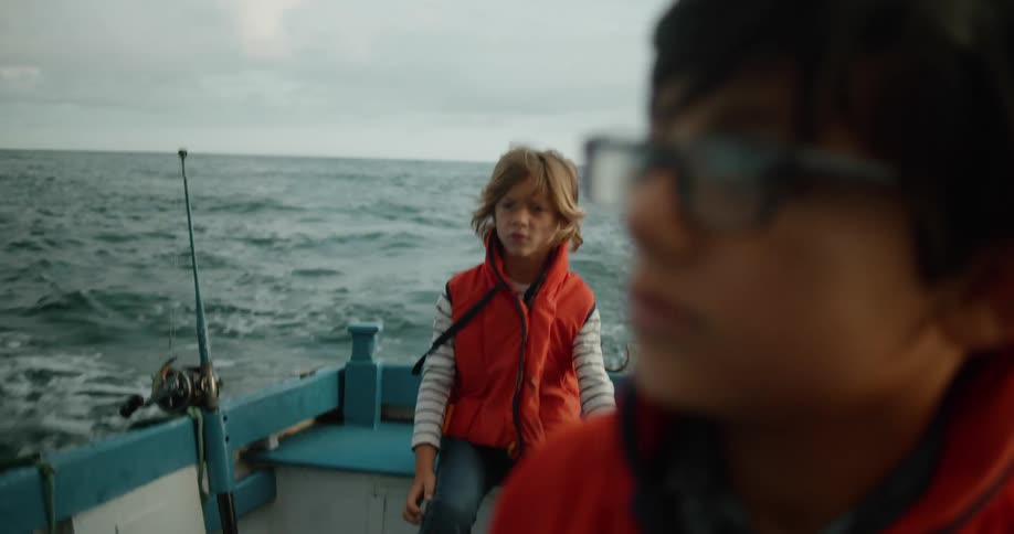 Family wearing bright red jackets sitting on a boat on a fishing trip in the ocean