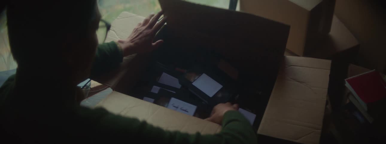 A man is looking at movies that were packed in a box