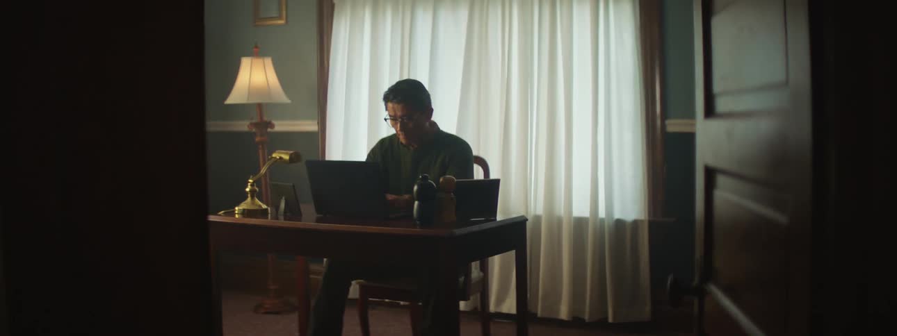 Man sitting at a desk on a peaceful room at home working on a laptop