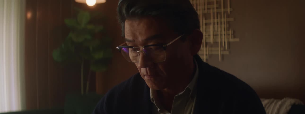 Man sits in living room viewing screen as eyeglasses reflect display