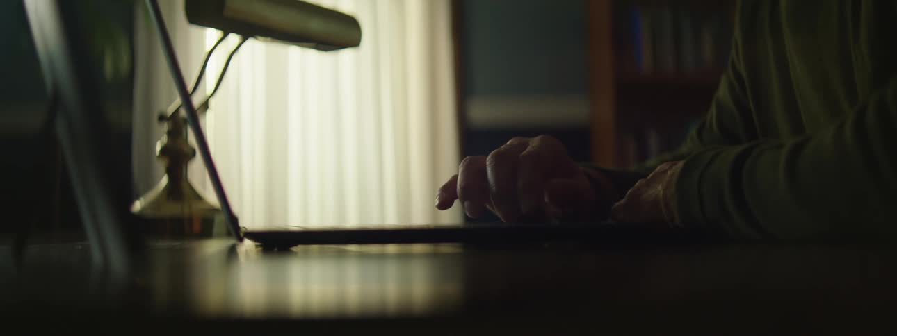 Close up of the hands of a person scrolling and typing on a laptop keyboard