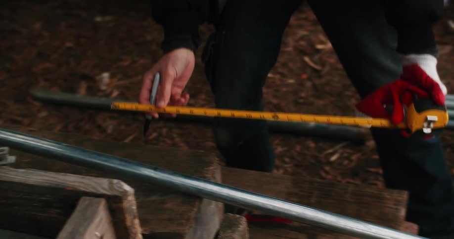 A farmer marks measurements before cutting