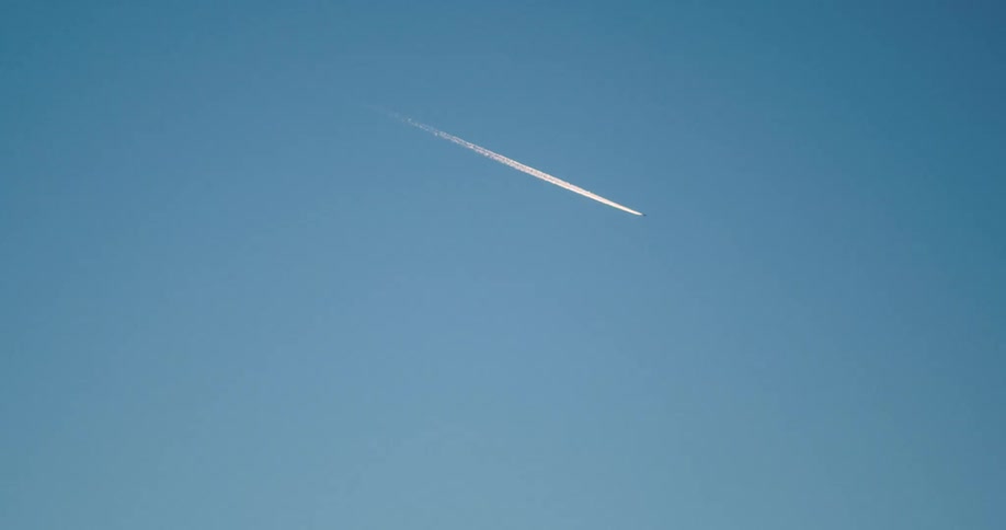 A jet plane leaves a contrail as it flies across the clear blue sky