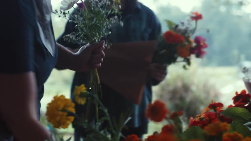 Two female workers assembling flower bouquets outdoorstion