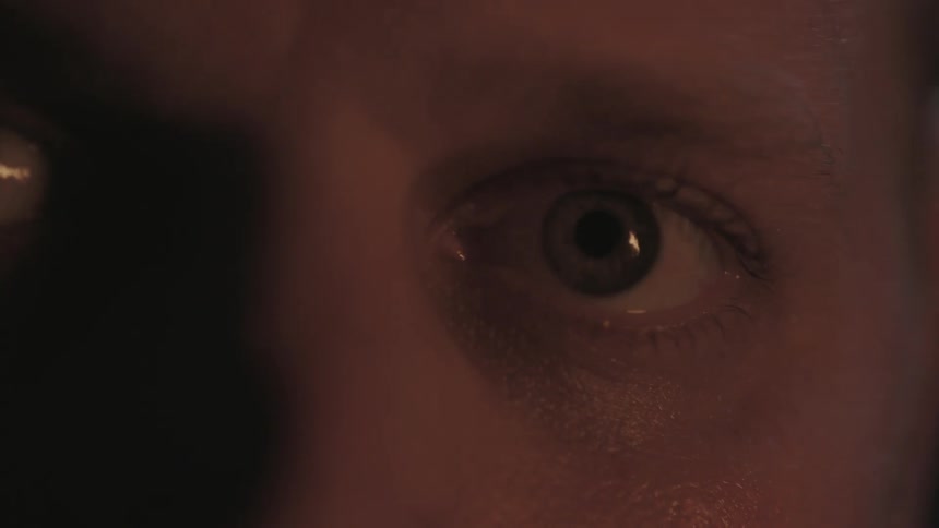 A burning fire illuminates a man's eye