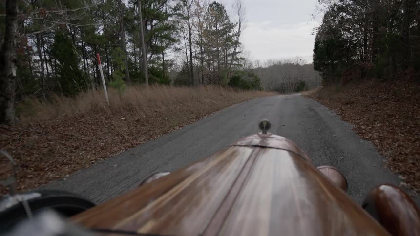 A vehicle drives on a road in the woods