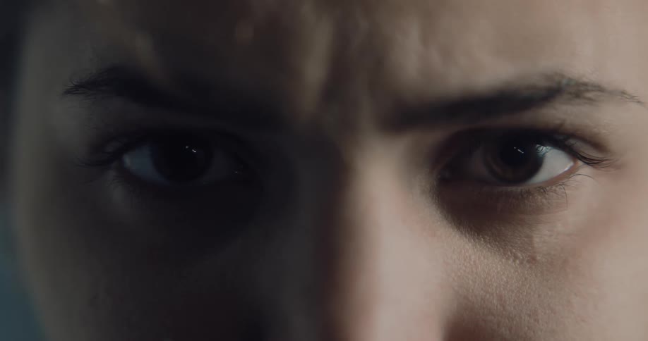 A close view of a woman staring into the camera while indoors