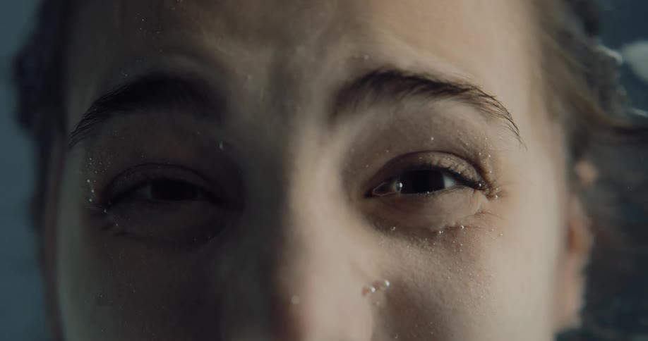 A person submerging their face in water and then opening their eyes underwater