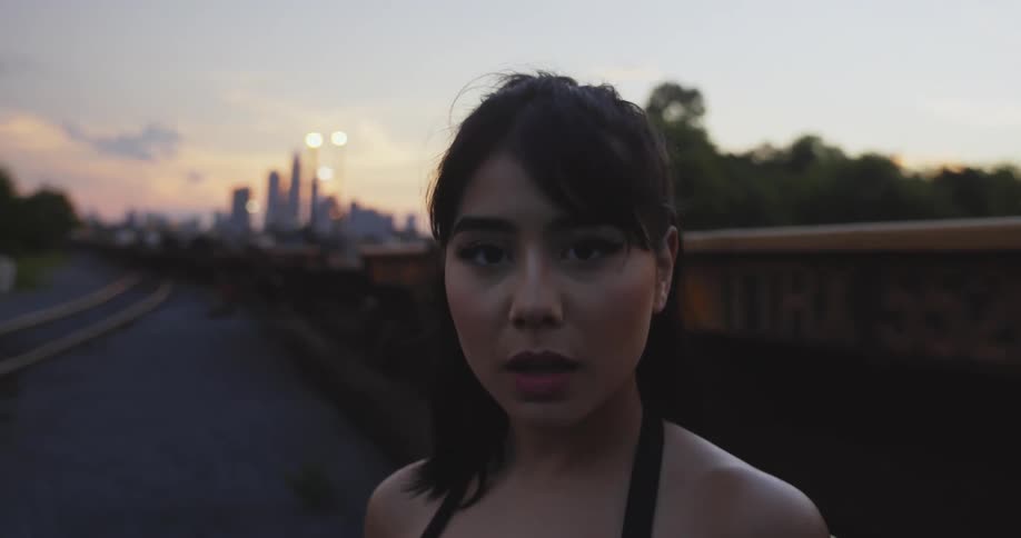 A young asian woman is outdoors standing in front of a train