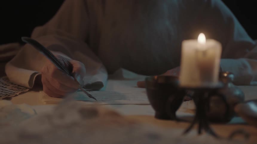 A man is writing by candle light