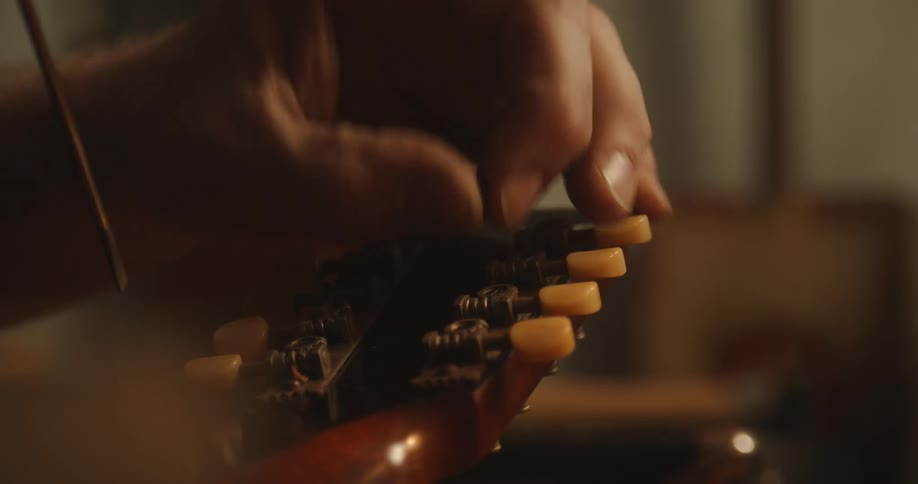 Hands using a tuner to tune a musical instrument