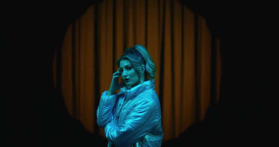 A woman with blonde pony tail with her hand on her face looking at the camera