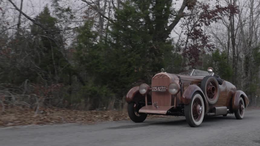 A classic car drives down a road