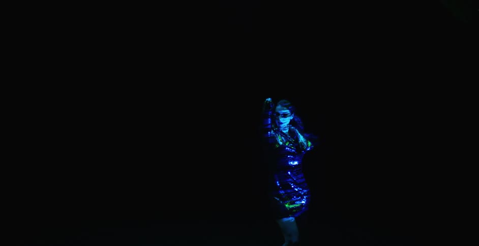 A female in a blue dress touching her hair against a black background