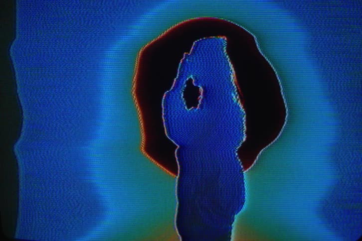 A womans silhouette fixing her jacket and hair with a fuzzy blue pixelation across the photo