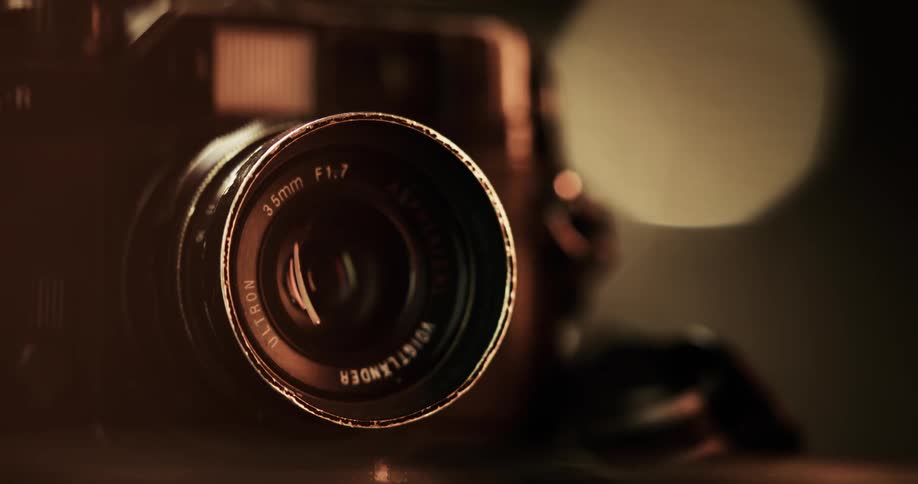Light shines on the 35mm camera lens of a camera on a table