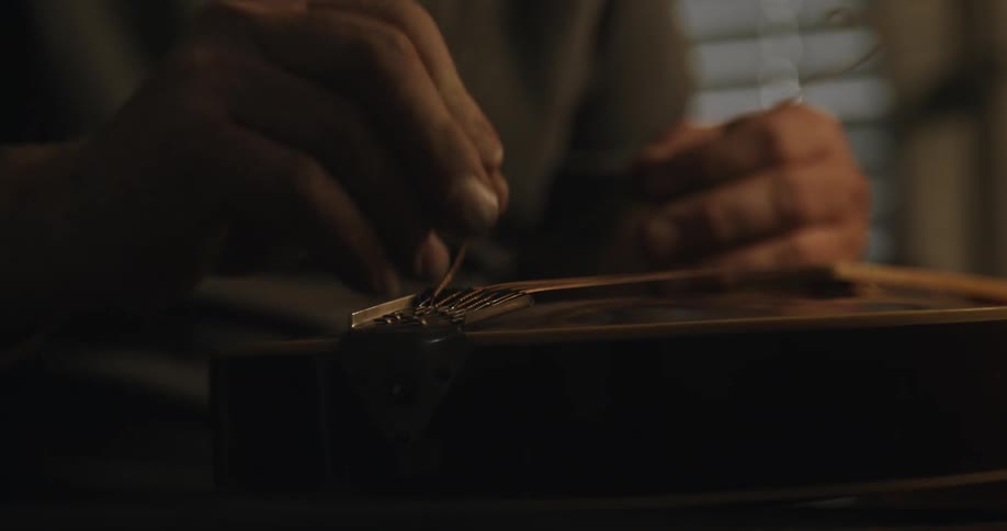 A man stringing a guitar with his hands