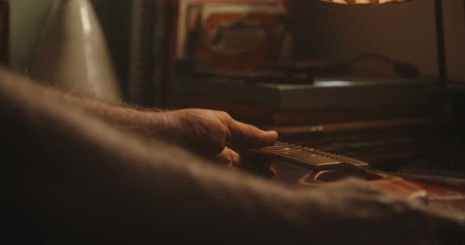 A man places a small stringed instrument onto a desk with a small neck support block
