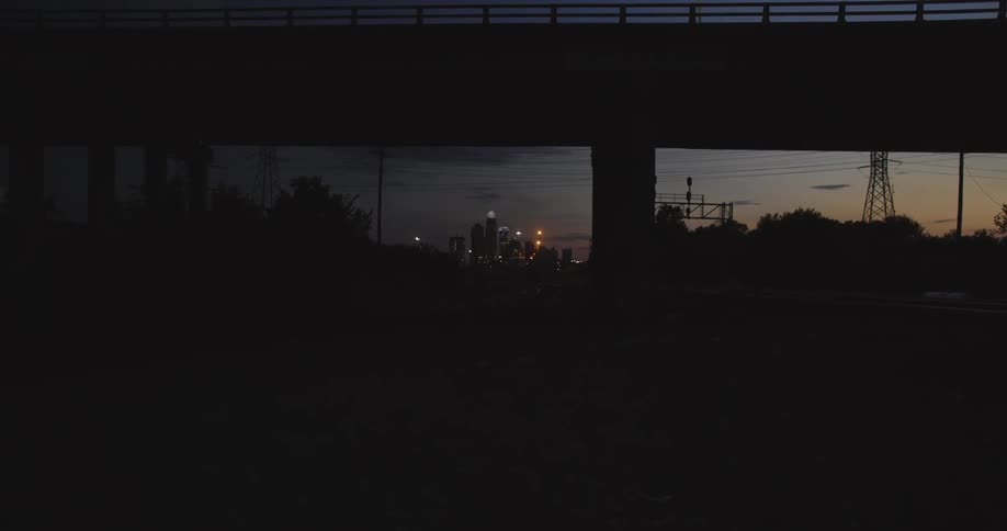 A car pulling in under a vehicle bridge during twilight