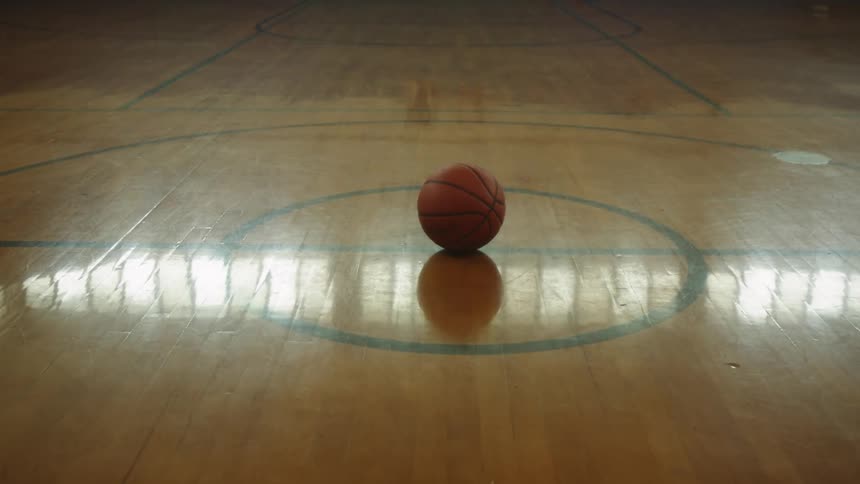 A basketball sits in the empty court