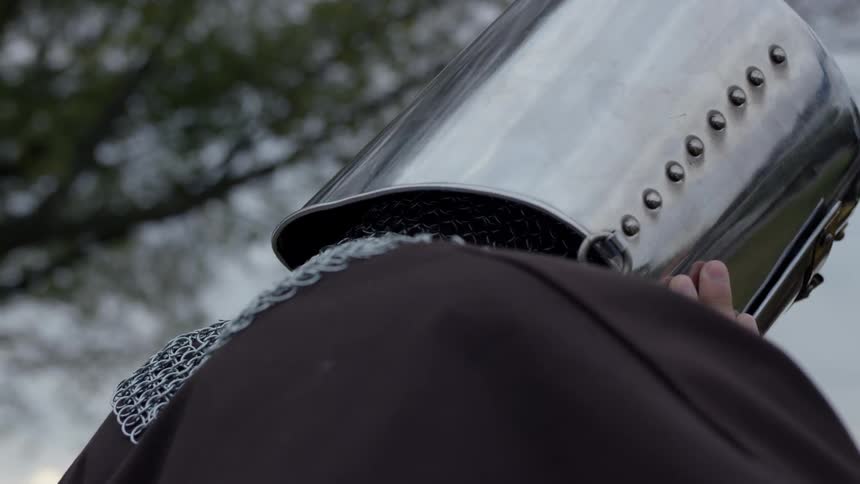 A man puts on a metal helmet