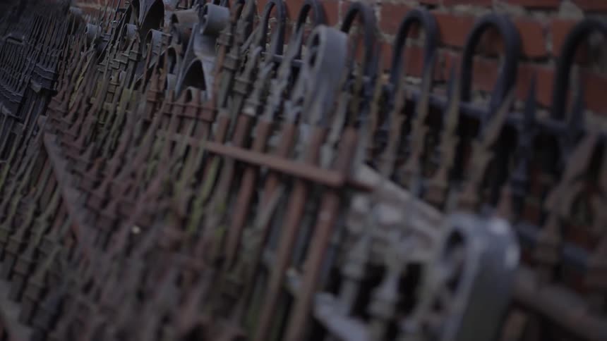 Iron fences are leaning against a brick wall