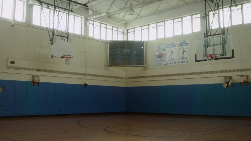 Basketball hoops hang from the ceiling in a gymnasium