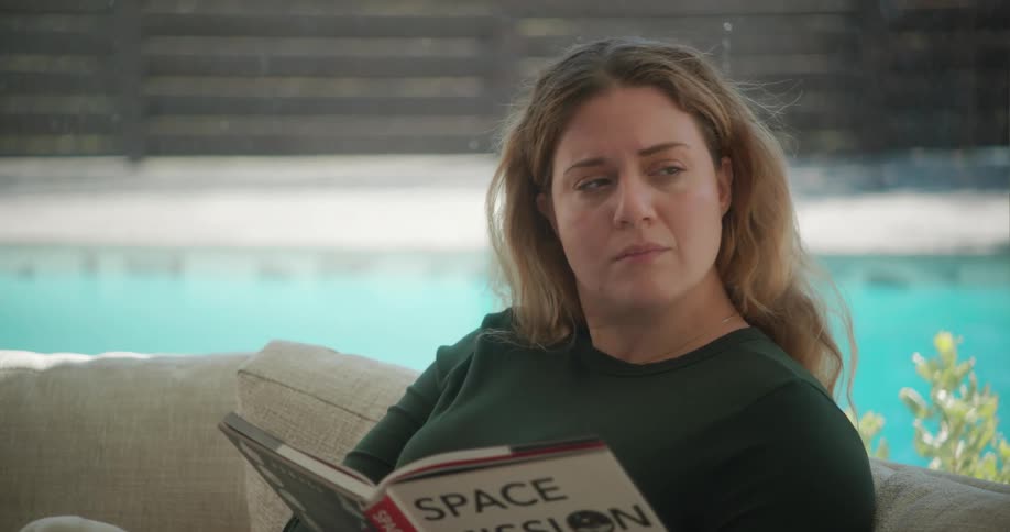 Thoughtful woman sitting on sofa at home reading a book