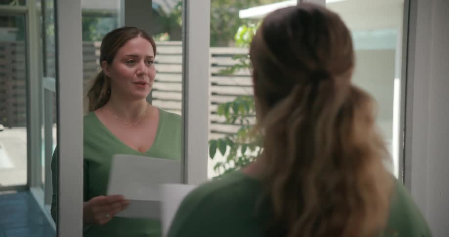 Nervous woman standing in front of the mirror holding papers and rehearsing some lines
