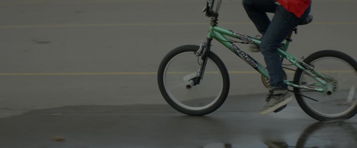 Boy riding a bike through a puddle of water