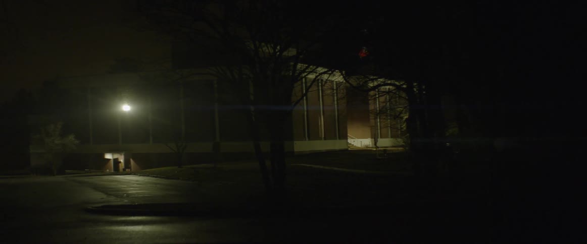 Two people hold flashlights outside of a stone building