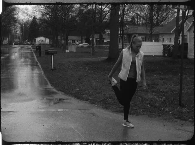 A woman is stretching outside as it rains