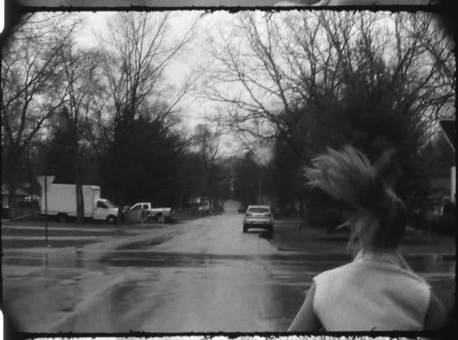A woman is running down a street in the rain