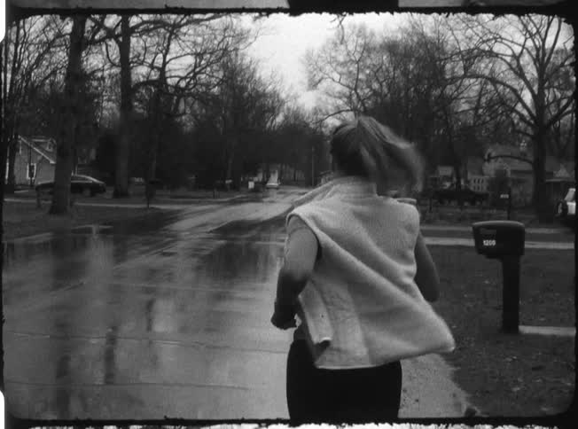 Girl with a ponytail jogging on wet pavement
