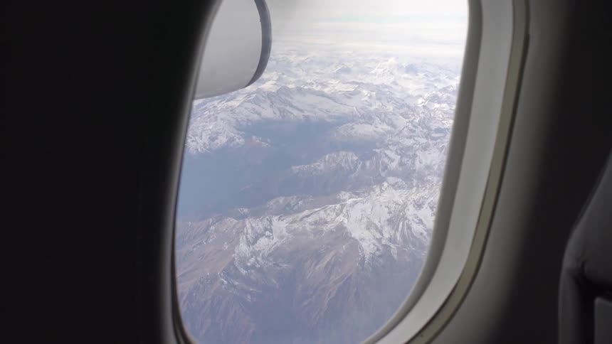 Outside of a plane window there are mountains below