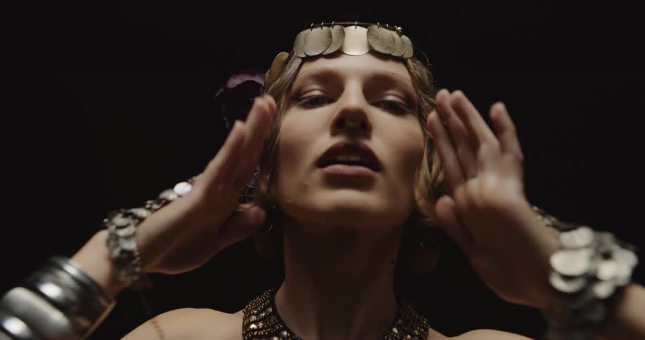 A woman is performing a belly dance in a darkened studio