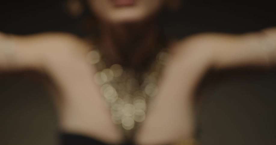 Belly dancer wearing bedlahheadbands with golden coins golden necklace and bracelets performs dance on stage